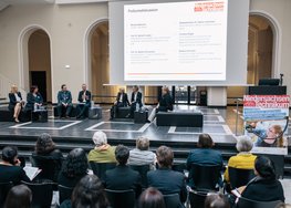 Blick von hinten auf die Podiumsdiskussion, Publikum zu sehen