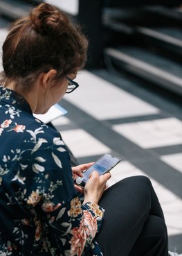 Blick von oben auf eine Frau, die ihr Smartphone in der Hand hat