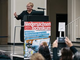 Eine Frau, stehend, spricht durch ein Mikrofon