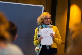 Frau mit Moderationskarten in der Hand, Fokus mit Blick aus dem Publikum